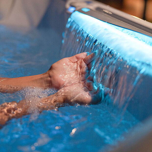 Zwei Hände unter einem kleinen Wasserfall eines Whirlpools