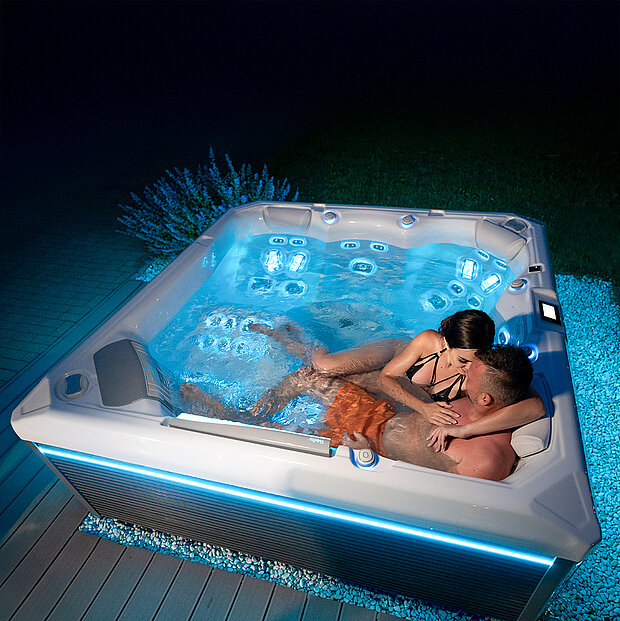 2 Personen in einem beleuchteten Whirlpool in der Nacht