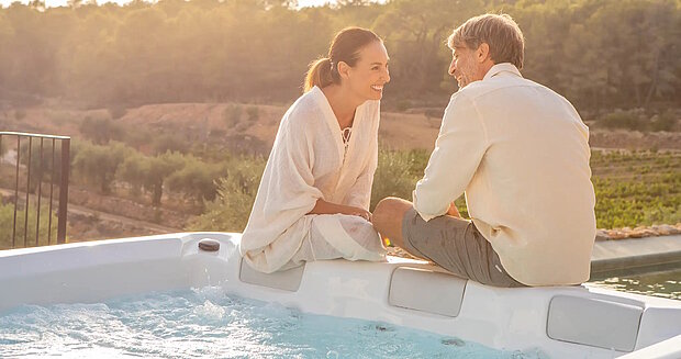 Ein Mann und eine Frau sitzen auf dem Rand eines Whirlpools